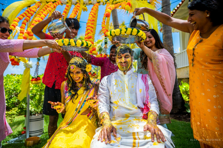 ndian wedding couple getting water poured on them during Haldi ceremony at Hyatt Grand Reserve