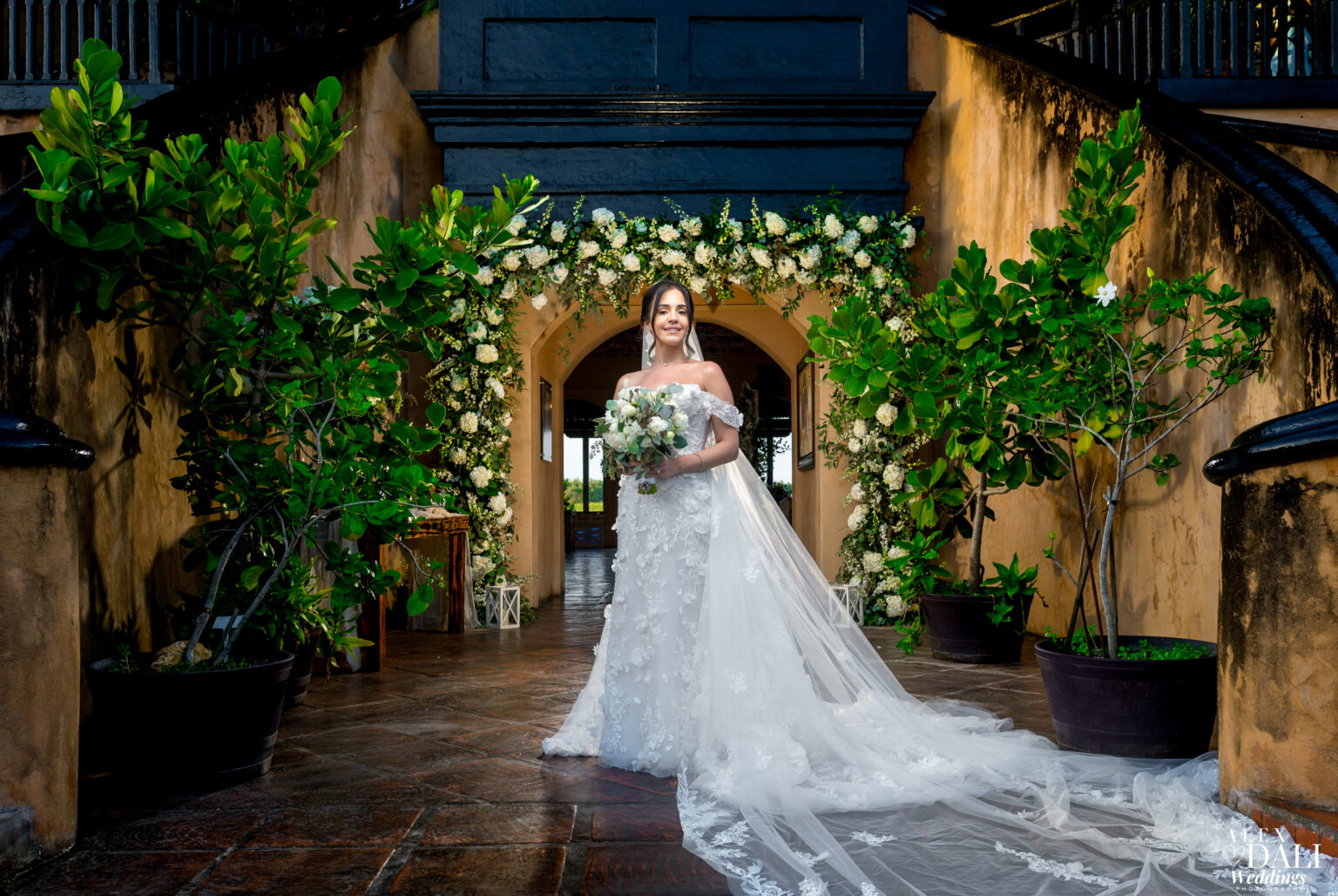 A stunning bride in a flowing white dress poses with a bouquet, surrounded by beautiful wedding decor at Hacienda Campo Rico.